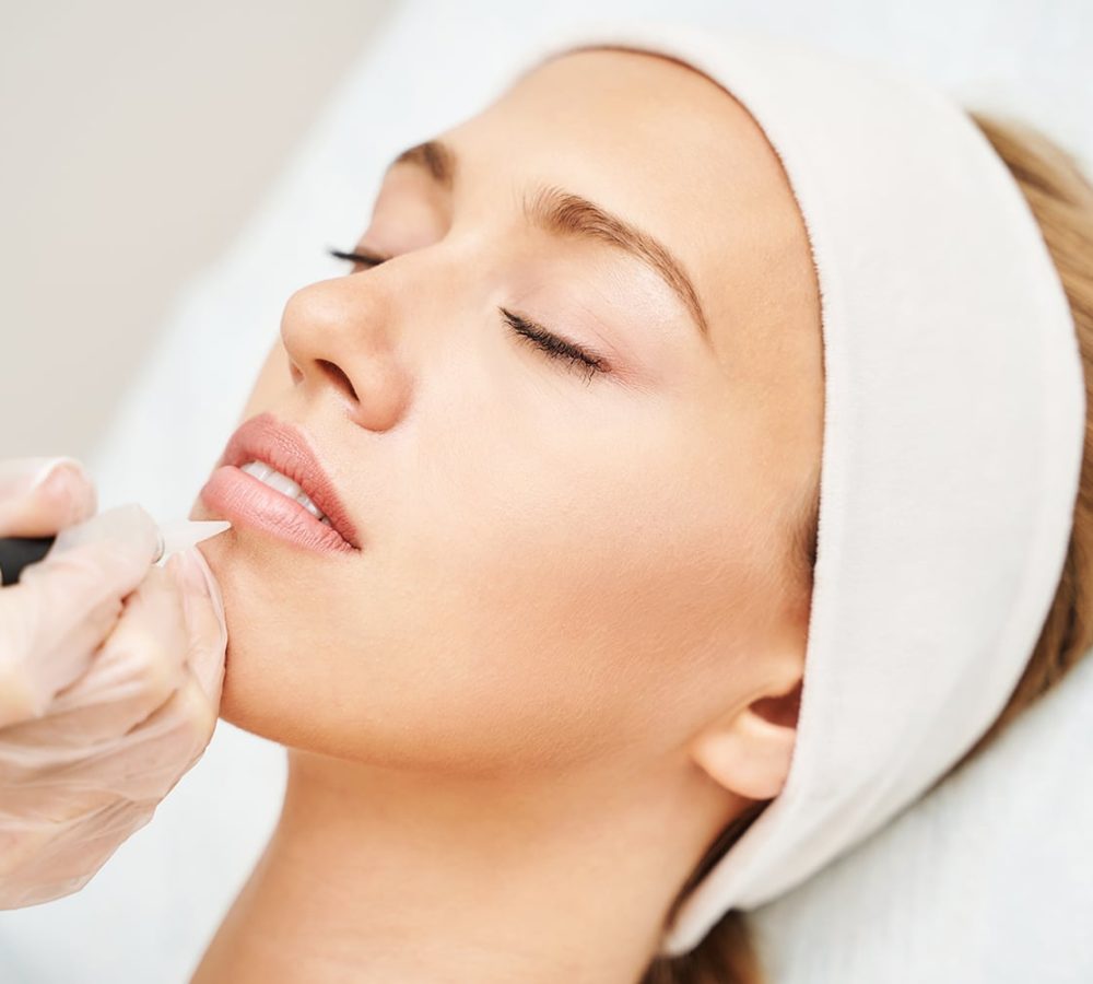 Young woman undergoing procedure of permanent lip makeup